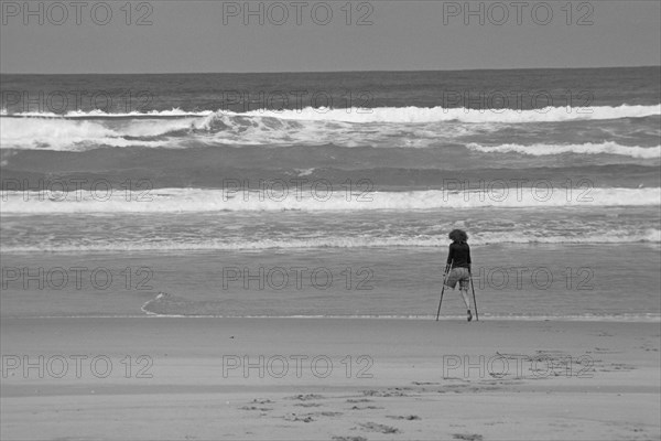 One-legged young woman on crutches by the sea