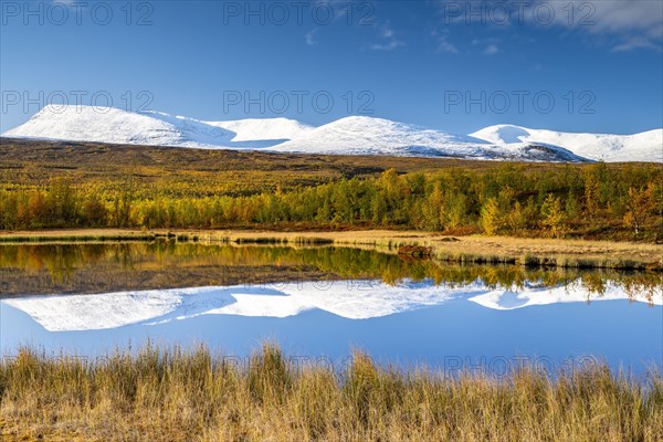 Snowy mountains of Abisko National Park reflected in small pond