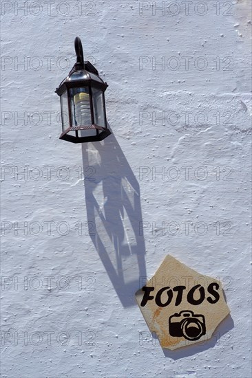 Stone slab with inscription Photos and lamp on house facade with energy-saving lamp