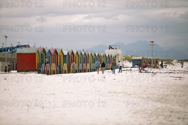Holidaymakers in front of colourful beach huts