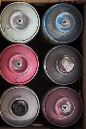 Six colourful spray cans in cardboard box