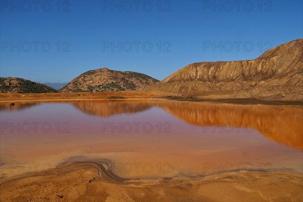 Mountains reflected in puddle on mine site