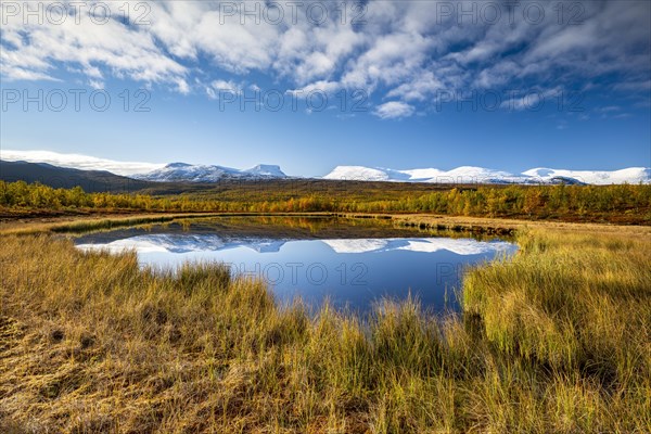 Mountain group Lapporten and snowy mountains of Abisko National Park reflected in small pond