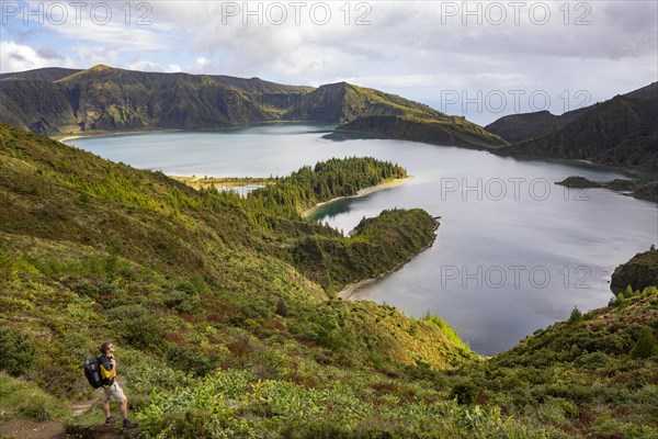 Hiker at the crater rim with view to the crater lake Lagoa do Fogo