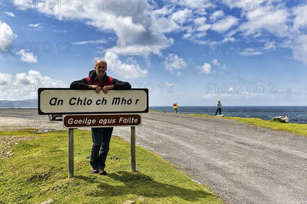 Tourist leaning against welcome sign in Irish