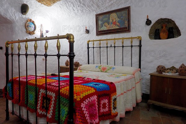 Bedroom with image of saint above bed in a cave dwelling