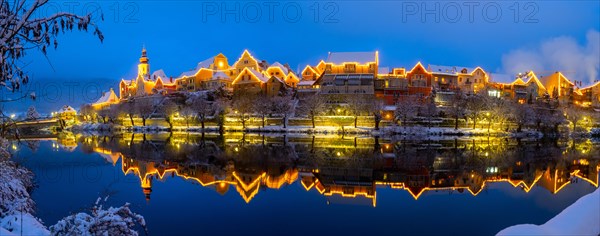 Christmas illuminated house facade of Frohnleiten reflected in the river Mur