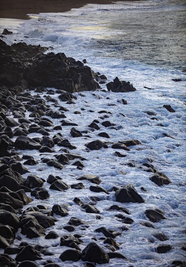 Large black lava stones in the surf on the beach of Praia de Santa Barbara