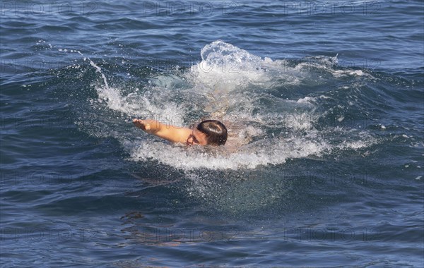 Young man swimming in the sea at the beach of Praia de Santa Barbara