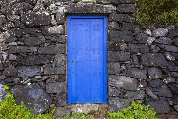 Lava stone garden wall with blue front door