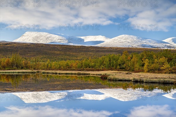 Snowy mountains of Abisko National Park reflected in small pond