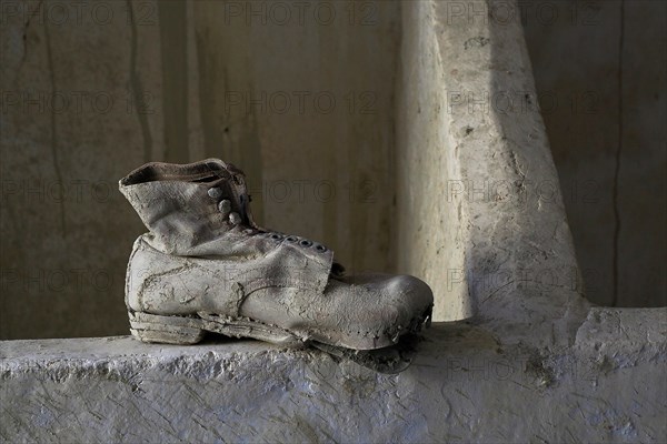 Old work shoe on the floor in front of wooden block