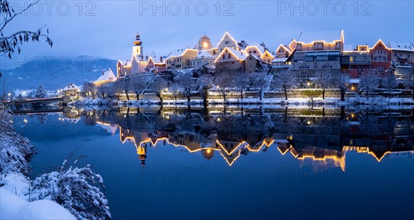 Christmas illuminated house facade of Frohnleiten reflected in the river Mur