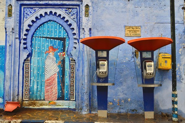 Door with painted woman next to two public telephones