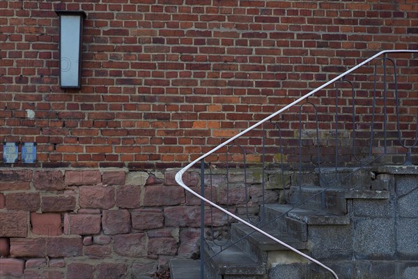 Stairs with railing in front of red brick wall