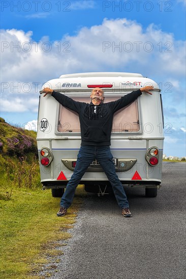 Man leaning against caravan at roadside