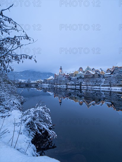 Christmas illuminated house facade of Frohnleiten reflected in the river Mur