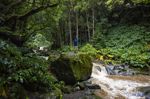Photographer on the hiking trail through jungle-like forest to the waterfall Salto do Prego