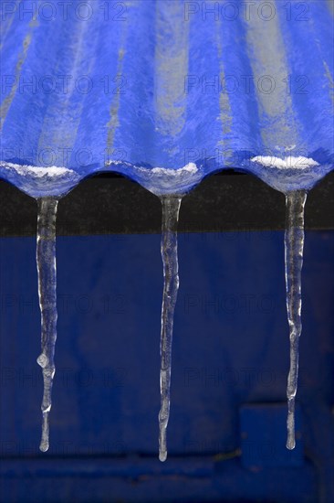 Three icicles on roof of blue corrugated iron