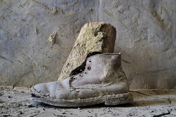 Old work shoe on the floor in front of wooden block