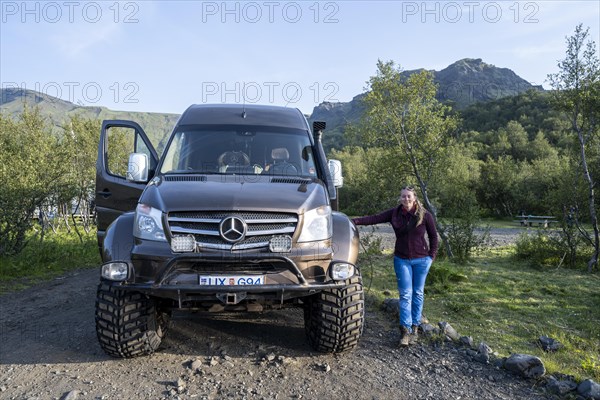 Young woman standing next to a large super jeep