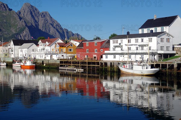 Fishing boats and houses reflected in the calm waters of a harbour