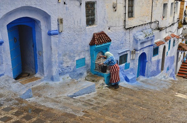 Woman at well in alley with stairs