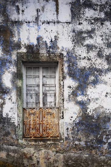 Weathered house facade with old closed window in Porto Formoso