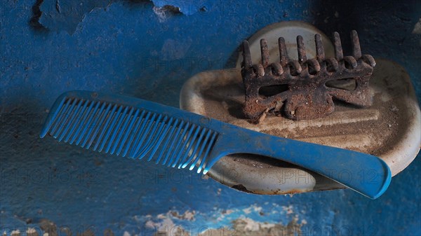 Old comb with hairclip in soap dish in front of blue wall