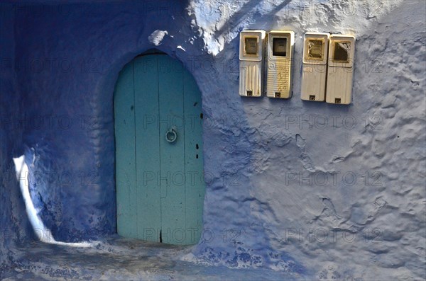 House with mint-coloured door with blue wall and four fuse boxes