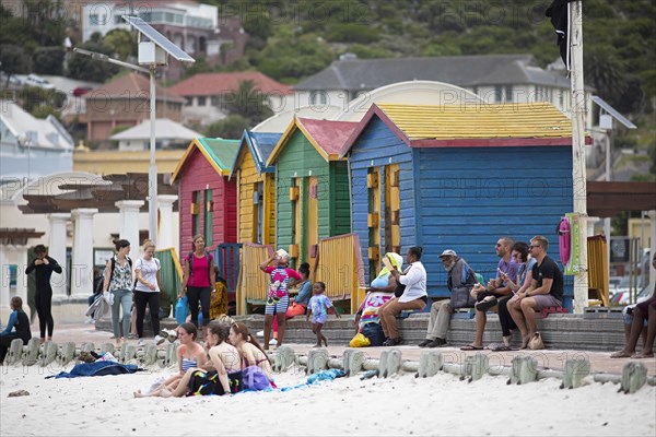 Holidaymakers in front of colourful beach huts