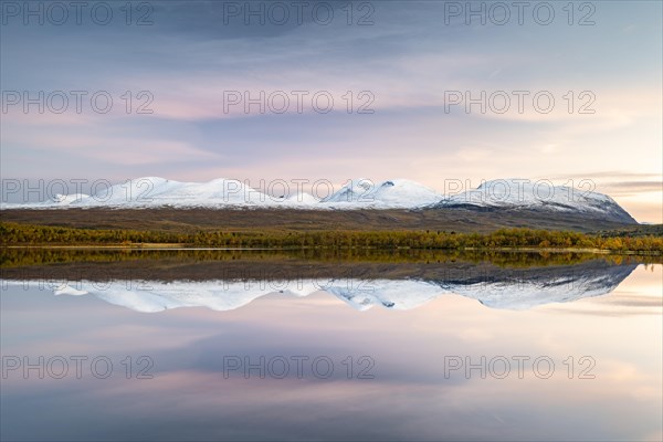 Snowy mountains in Abisko National Park reflected in lake Vuolio Njahkajavri