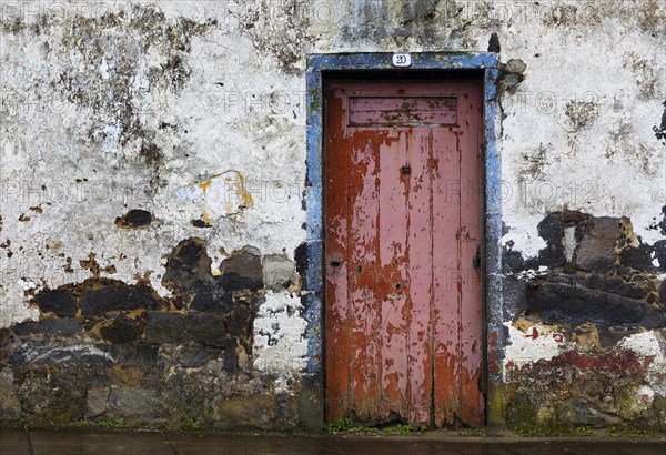 Weathered house facade with old closed red front door in Porto Formoso