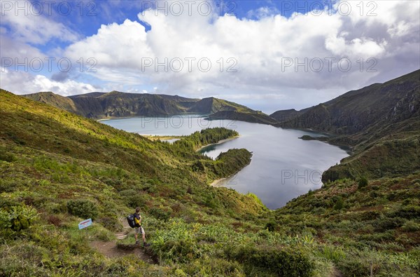 Hiker at the crater rim with view to the crater lake Lagoa do Fogo