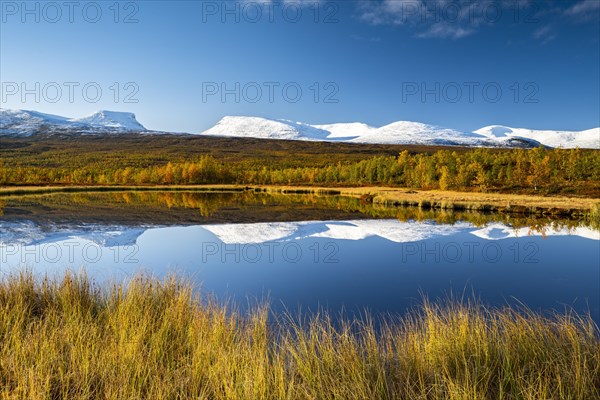 Mountain group Lapporten and snowy mountains of Abisko National Park reflected in small pond