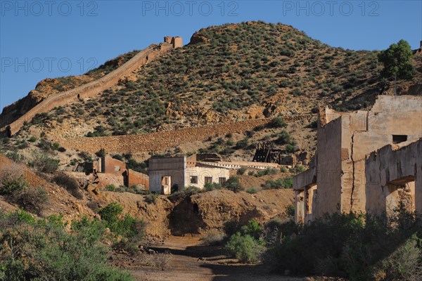 Mine ruins with winding tunnel against a mountainous backdrop