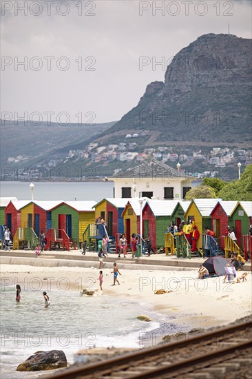 Holidaymakers in front of colourful beach huts