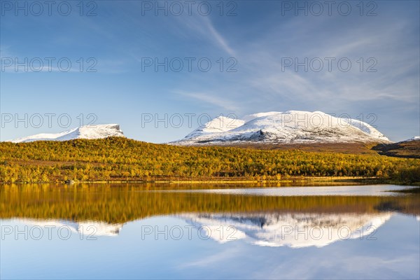 Snowy mountain group Lapporten reflected in lake Vuolio Njahkajavri