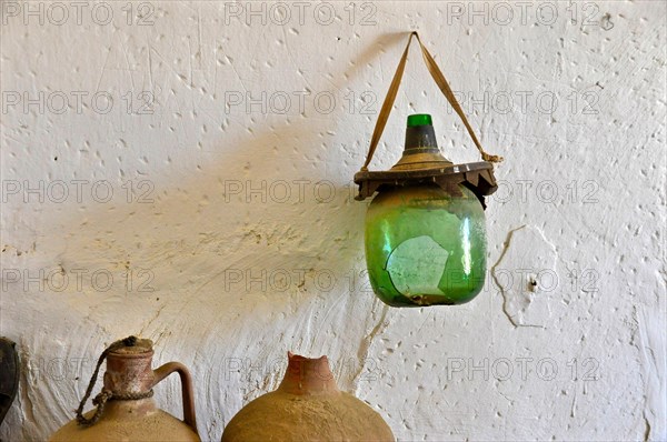 Clay jugs and broken wine bottle in front of white wall