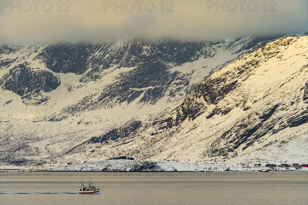 Fishing boat in winter Scandinavian landscape at the fjord