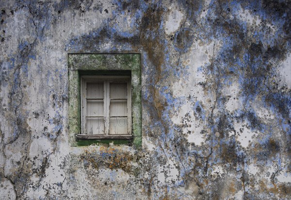 Weathered house facade with old closed window in Porto Formoso