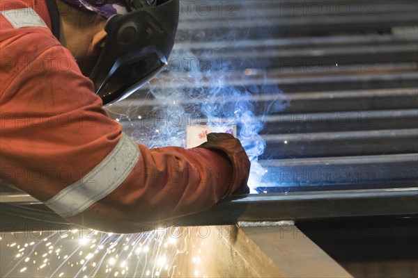 Factory worker welding in a manufacturing plant