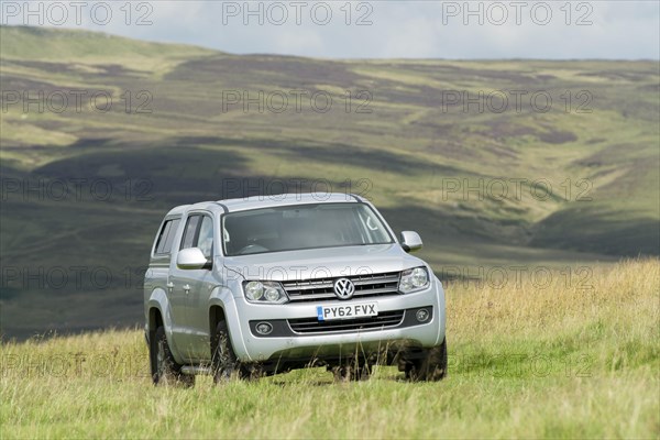 Four wheel drive VW Amarok twin cab pick up driving across upland pasture in North Yorkshire