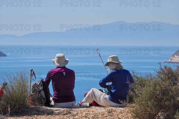 Man and woman resting on trail by the sea