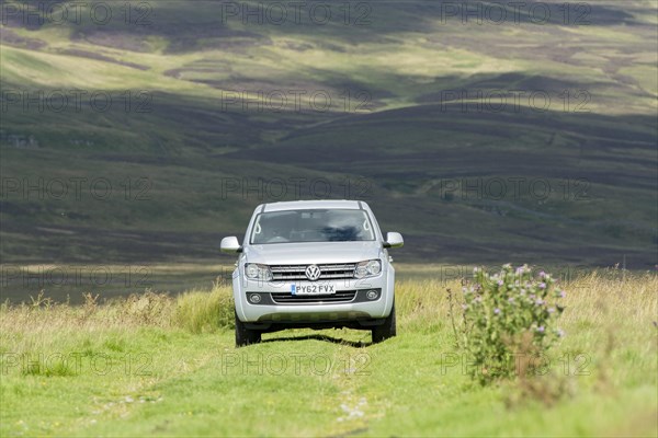 Four wheel drive VW Amarok twin cab pick up driving across upland pasture in North Yorkshire