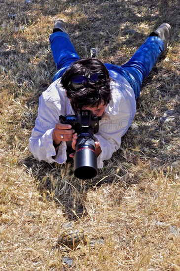 Photographer lying on her stomach with telephoto