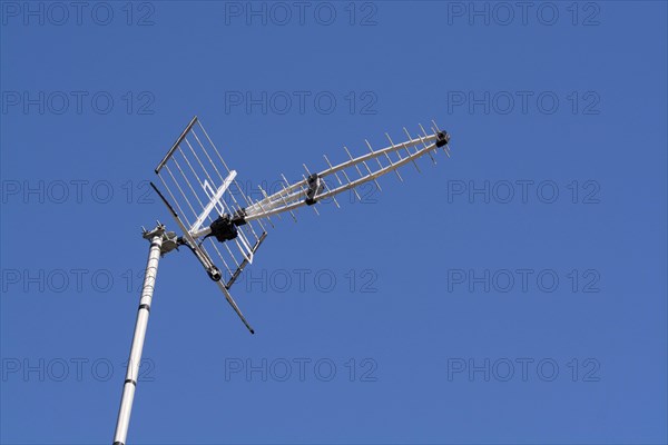TV aerial on house against clear blue sky. UK