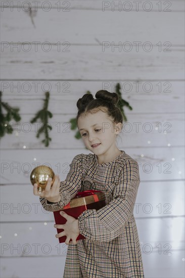 Girl with Christmas present in front of a Christmas backdrop