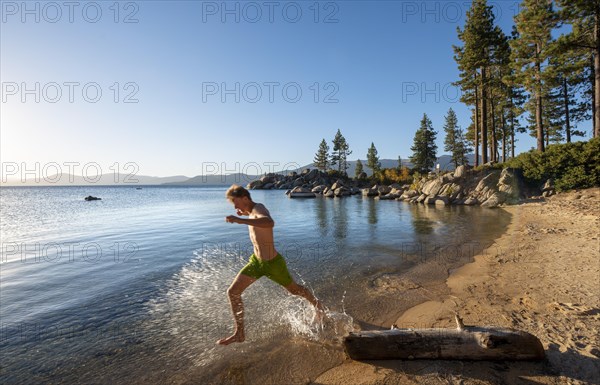 Young man running in the water on a sandy beach