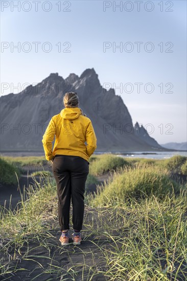 Young woman with rain jacket walks through dune